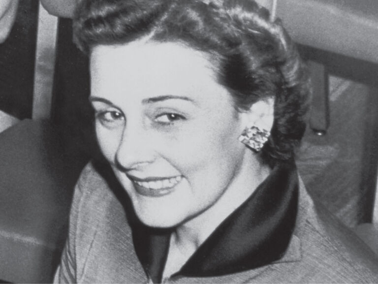 Vintage photo of Mary Kay founder wearing elegant suit and statement earrings.