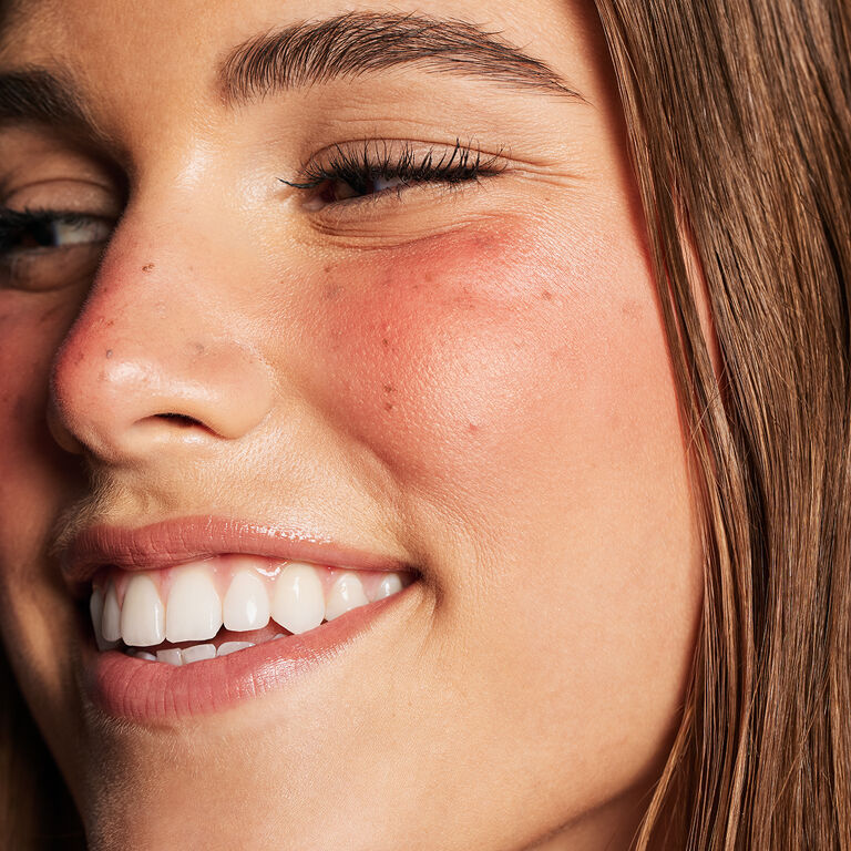 Model with blonde hair and rosy cheeks looking to the left